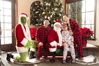 Festive family photo with Santa Claus, the Grinch, and Christmas tree indoors.